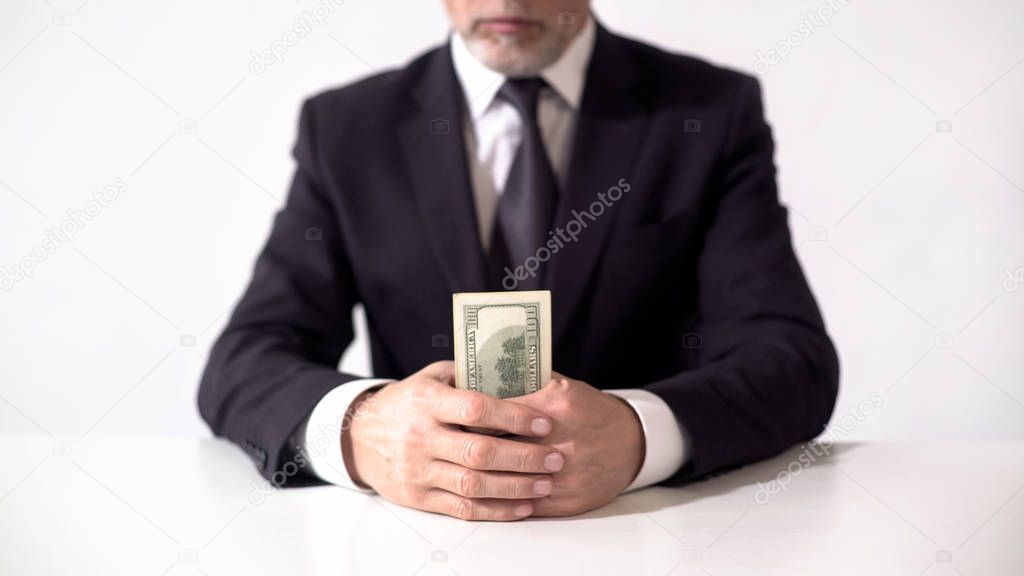 Rich man holding bundle of dollar banknotes, businessman estimating income
