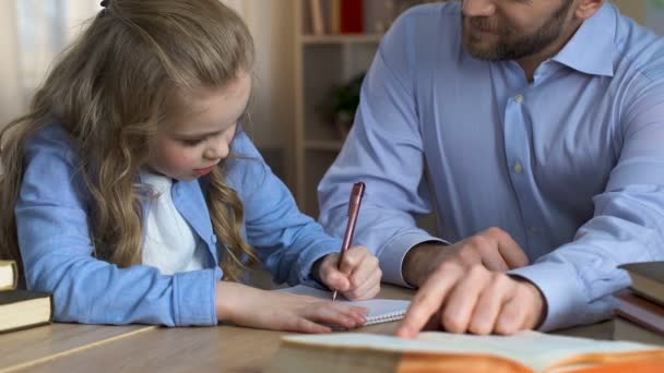 Chica aprendiendo a escribir con ayuda del padre, apoyo familiar, pasar tiempo juntos — Vídeos de Stock