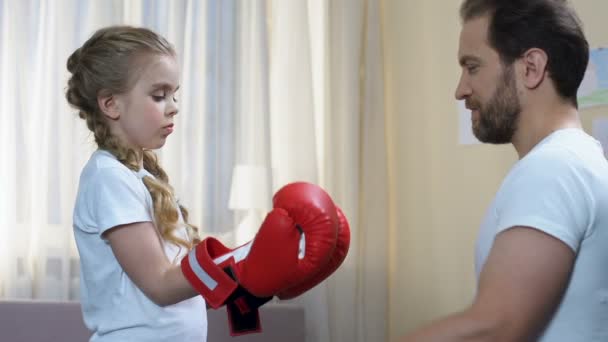 Padre deportivo ayudando a su hija a ponerse guantes de boxeo, entrenamiento en casa, defensa propia — Vídeos de Stock