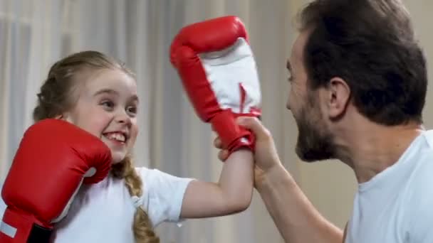 Père souriant se sentant fier de sa fille après une partie de boxe, soutien familial — Video