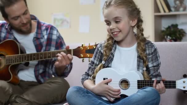 Babası gitar ve kızı ukulele oynarken şarkı, yaratıcı eğlence, prova — Stok video