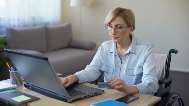 Niza mujer mayor en silla de ruedas número de tarjeta de escritura en el ordenador portátil, el pago de facturas — Vídeos de Stock