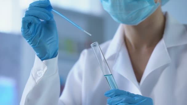 Test tüpü içinde mavi sıvı damlayan ve reaksiyon analiz kadın laboratuar işçisi — Stok video