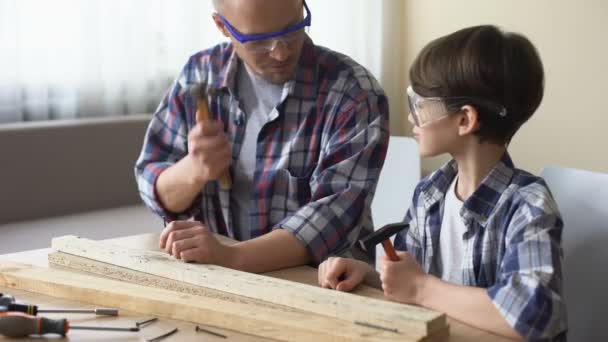 Dad teaching little son how to use hammer safely, family leisure, hobby and fun — Stock Video