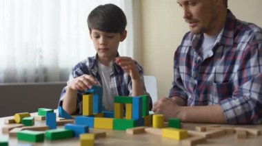 Baba ve ciddi oğul birlikte, ev inşa oyuncak küpleri ile eğlence iskambil