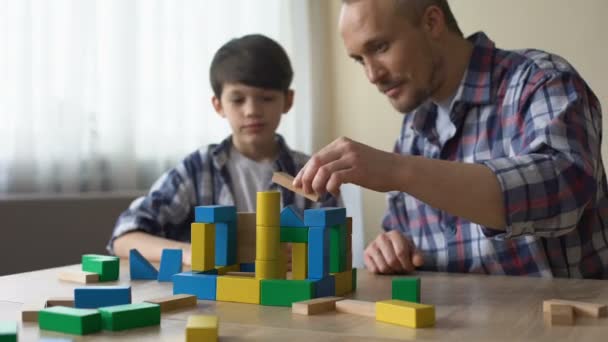 Cuidar papá y su hijo sonriente jugando cubos de juguete de colores en casa, la infancia — Vídeos de Stock