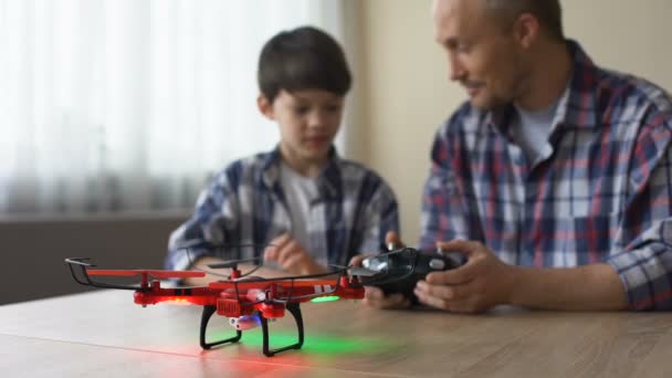 Pai engraçado ajudando filho a usar controle remoto de quadrocopter, tecnologias — Vídeo de Stock