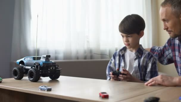 Lindo niño y su padre operando un coche controlado por radio en casa, tecnologías — Vídeos de Stock