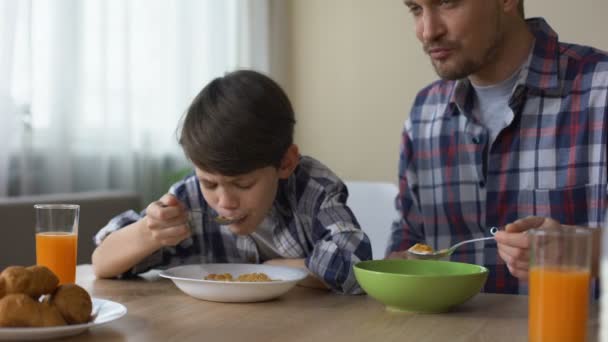 Rád, syn a otec jíst chutné kukuřičné lupínky u snídaně, ranní tradice