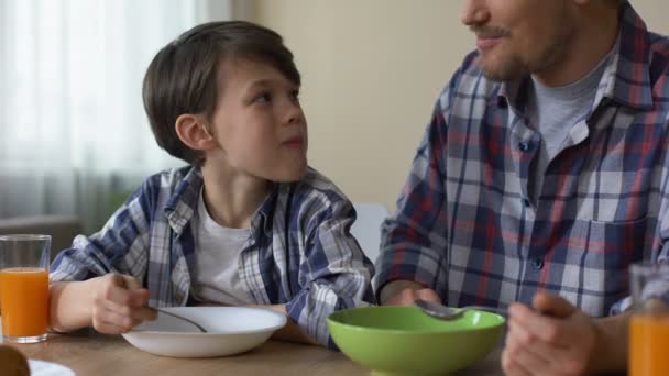 Pai e filho tomando café da manhã juntos, comendo saborosos flocos de milho manhã em casa — Vídeo de Stock