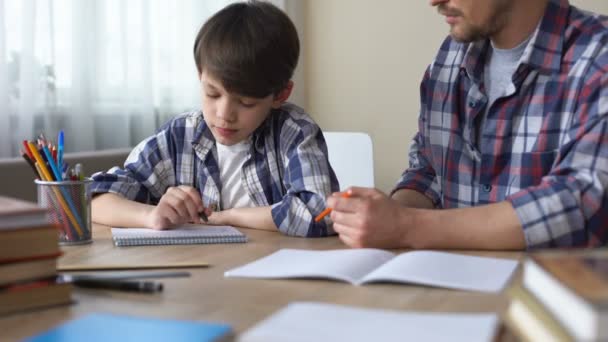 Father and son doing homework together, dad explaining task, school education — Stock Video