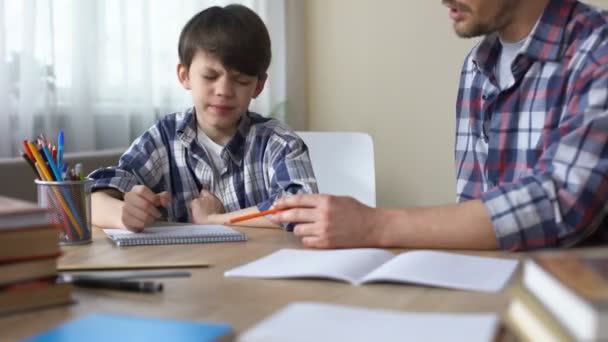 Papá sentado en la mesa y haciendo que su hijo caprichoso haga la tarea, la educación — Vídeo de stock