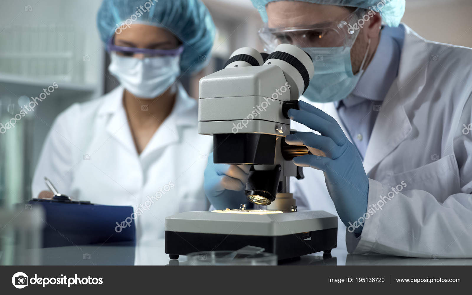 Researcher Viewing Sample Microscope Assistant Taking Notes Laboratory