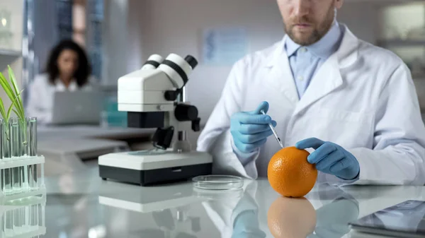 科学家橙色注射特殊物质检查化学品的数量 — 图库照片