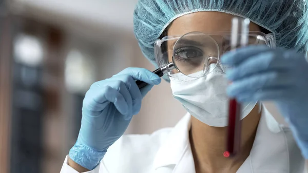 虫眼鏡 分析を通じて血液検査を見て女性医療従事者 — ストック写真