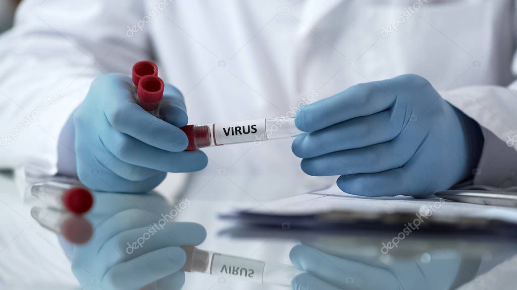 Chemist holding virus vaccine tube, writing report of laboratory experiment