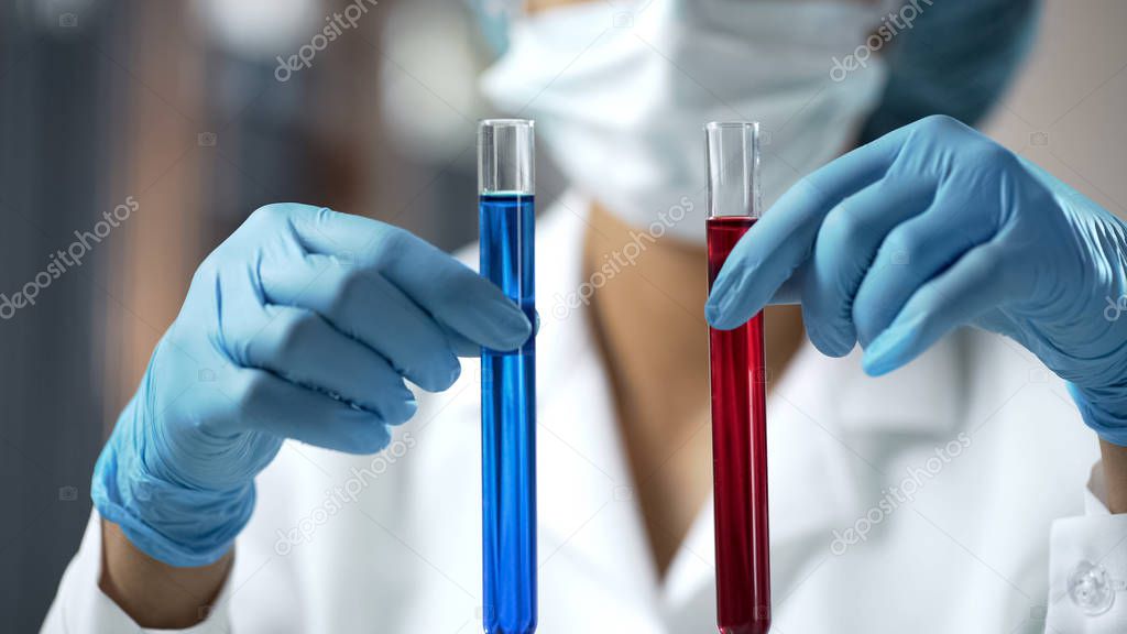Scientist holding two test tubes with red, blue liquid at laboratory, research