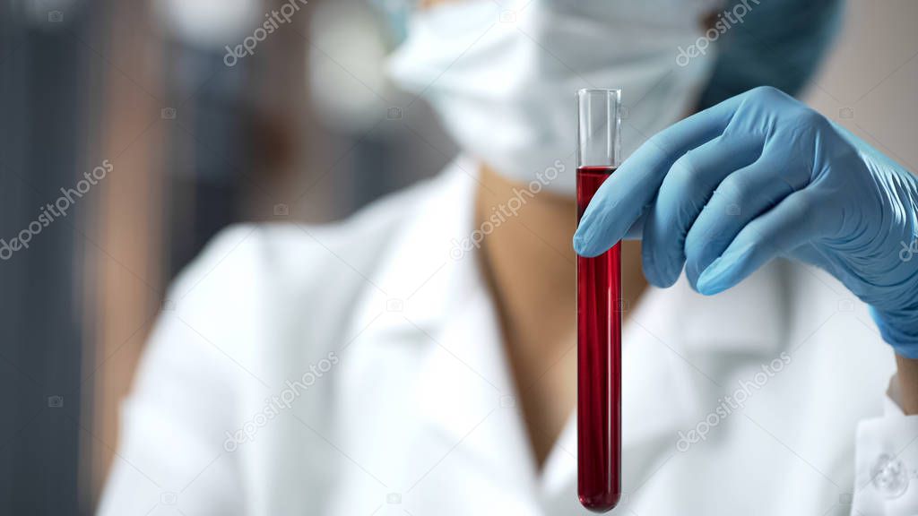 Lab assistant holding test tube with red liquid, blood analysis researching