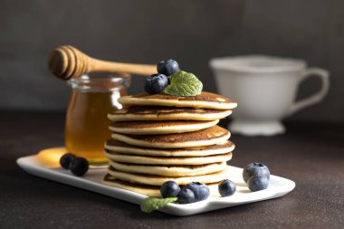 Masada yaban mersini ve beyaz tabakta bir yığın krep. Ballı ve yaban mersinli krep. Lezzetli ev yapımı kahvaltı..
