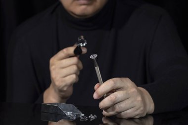 Elması yuvarlak tutan bir kuyumcu. Mücevher işi. Elmas endüstrisi. Kesip parlatılmış elmaslar. Loupe, büyüteç. Elmas aletler. Gevşek elmas. Luxary mücevher taşları. Değerli taşlar. Elmas satışları, gringleme, ticaret.