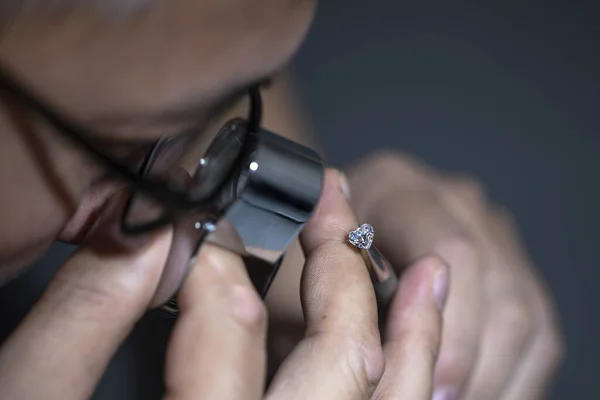 Man jeweller holding round shape diamond. Jewellery business. Diamond industry. Cut and polished diamonds. Loupe, magnifier. Diamond tools. Loose diamond. Luxary gem stones. Precious stones. Diamond sales, grding, trading.