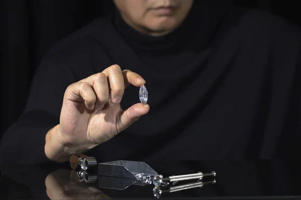 Man jeweller holding round shape diamond. Jewellery business. Diamond industry. Cut and polished diamonds. Loupe, magnifier. Diamond tools. Loose diamond. Luxary gem stones. Precious stones. Diamond sales, grding, trading.