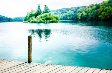 Plitivice Ulusal Parkı, Hırvatistan, 26 Ağustos 2019. Gölde tekne gezisi. Direk ve tahta köprü. Nesneden daha önemli bir arkaplan. Avrupa 'da dramatik bir istikamet. 