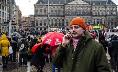 Amsterdam / Hollanda 18 Ocak 2020: Ocak 2020 'de Lale Festivali sırasında Amsterdam Baraj Meydanı' nda cep telefonuyla konuşan bir adam