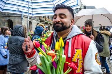 Amsterdam / Hollanda 18 Ocak 2020: Lale Festivali için Amsterdam Barajı Meydanı 'nda kırmızı ceketli ve şemsiyeli bir adam