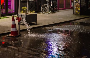 Gece vakti Rotterdam Hollanda 'daki borulardan su sızıyor. Arka plandaki patikada bisiklet.