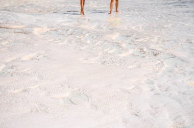 Pamukkale beyaz tortulu kayaların üzerinde yürüyen iki kişi..