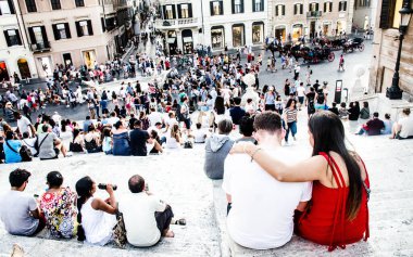 Roma 'da tarihi İspanyol Merdivenleri' nde oturan çift ve kalabalık.