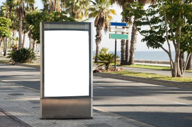 Şehir merkezindeki yol üzerinde palmiye ağaçları olan ilan panosu.