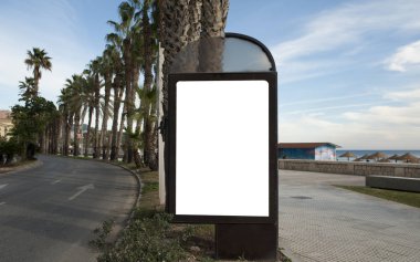 Şehir merkezindeki otoyol ayrımında palmiye ağaçları ve mavi gökyüzü ile yürüyen reklam panosu.