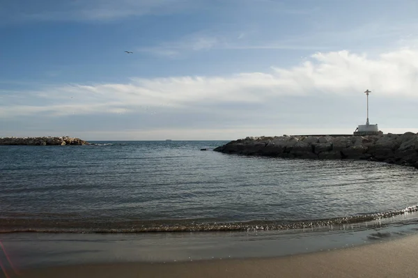 Relaxing beach with gentle waves reaching the sea breakwater sand with lamppost and rocks