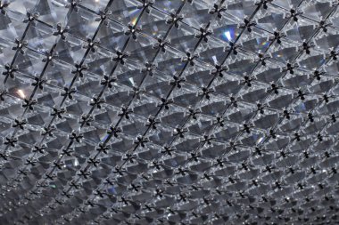 Metal parçalarıyla bir arada tutulan çok renkli röfleli kristal parçaları. Dipte bulanık