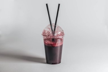 İçi yabanmersinli ve tüplü plastik bir bardak.