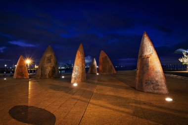 Geelong waterfront art structures resembling either fins or sails taken on a long exposure at twilight .