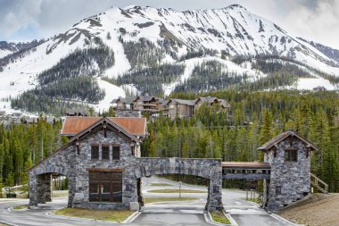 Montana, Usa 2011 Ay Işığı Havzası kemerli kapı girişi çam ağaçları ve dağlara karşı. Moonlight Havzası, Büyük Gök 'ün tatil köyü Rocky Dağları' nın Madison Range 'inde bir kayak merkezidir..
