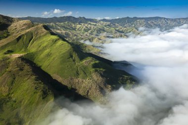 fiji aerial of green mountains with deep valleys and thick white fog on a sunny day. Yasawa island group in Fiji, South Pacific clipart