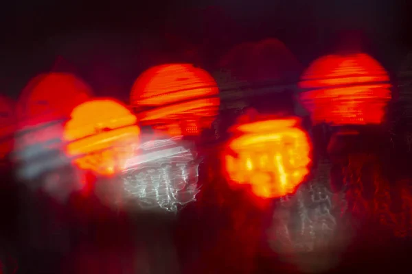 abstract bokeh caused by rain drops reflecting onto car windscreen from car brake lights and night city street lights. Indistict focus applied.