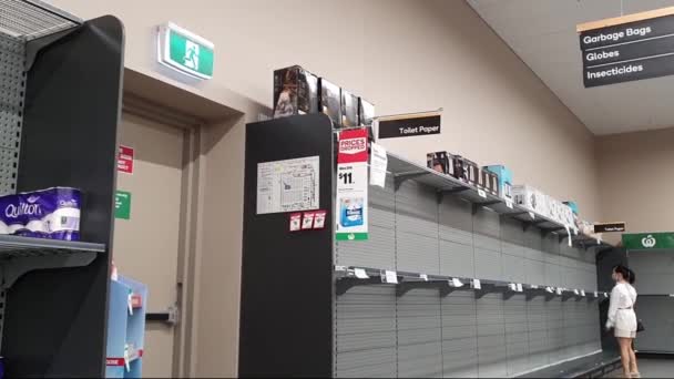 金海岸 オーストラリア 2020年4月9日 コロナウイルスの恐怖の中でスーパーマーケットの空のトイレタリーペーパー棚 医療面マスクパニックを持つアジアの女性トイレペーパーの購入と備蓄 Covid 19パンデミック — ストック動画