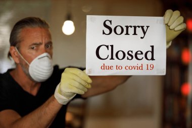 Coronavirus iş konseptine kapalı, tıbbi maskeli erkek işyeri sahibi, Cavid 19 virüs salgını, kafeterya iflası, covid-19 kısıtlamaları ve tecrit süresince pencereye üzgün kapalı tabela astı