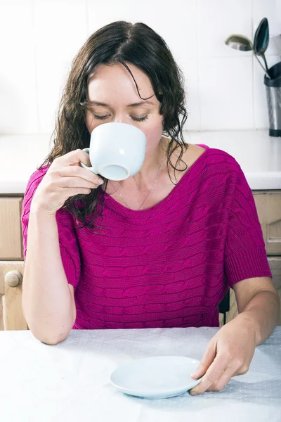 Hermosa morena con taza de café en la cocina — Foto de Stock
