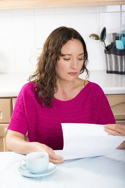 Mulher perturbada com documentos na cozinha — Fotografia de Stock