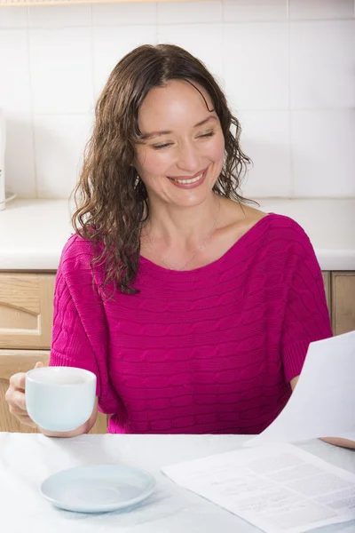 Happy brunette with documents in kitchen — Stock Photo, Image