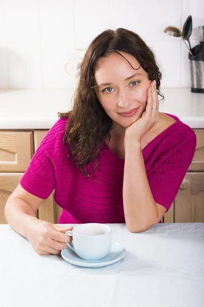 Beautiful brunette with cup of coffee in kitchen — Stock Photo, Image