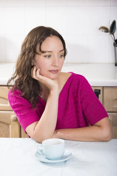 Tired brunette with cup of coffee in kitchen — Stock Photo, Image