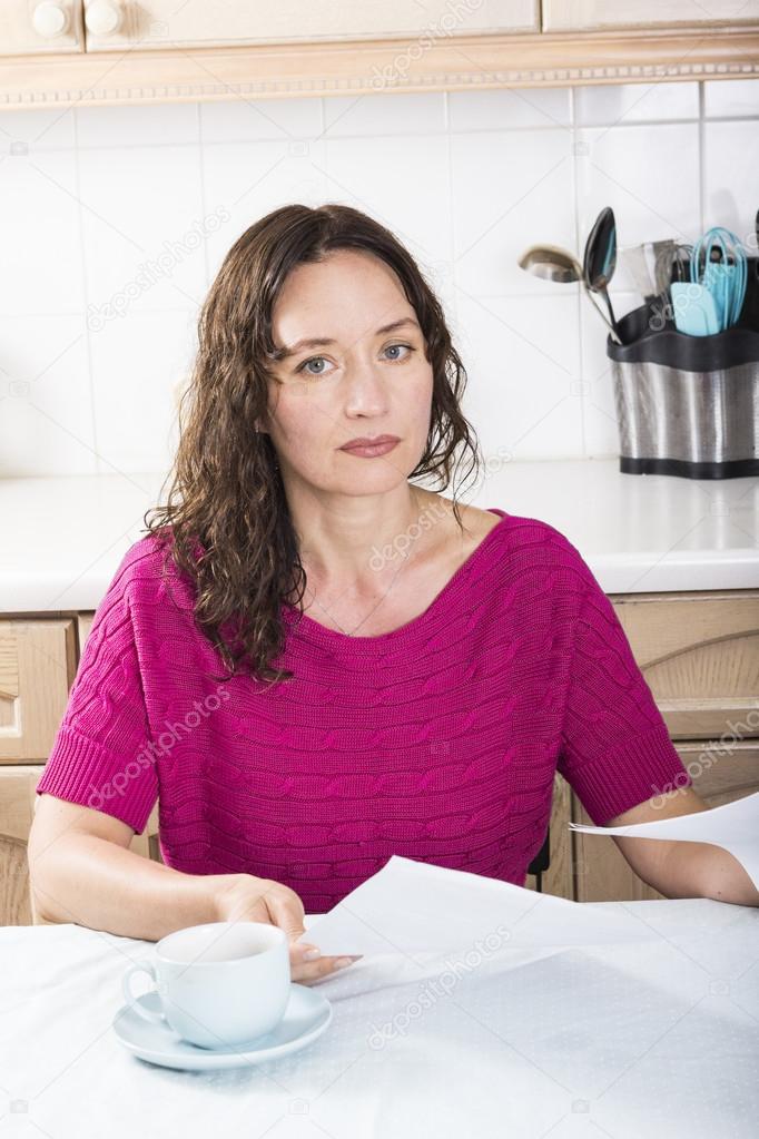 Upset woman with documents in kitchen