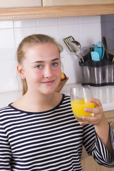 Menina com copo de suco na cozinha — Fotografia de Stock